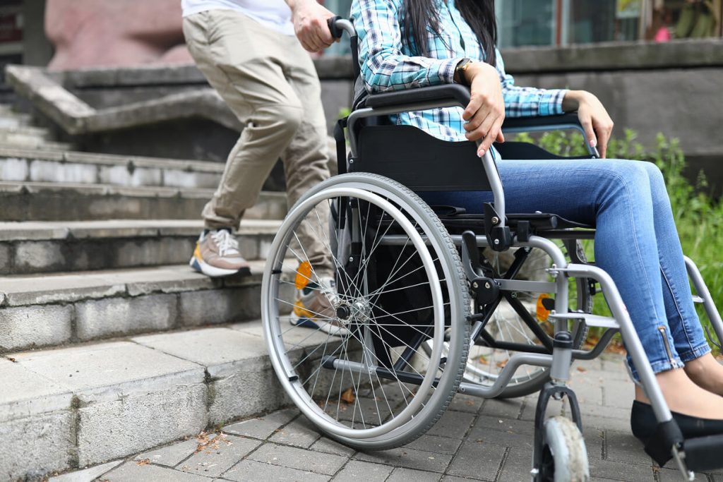 A person in a wheelchair being assisted up a set of stairs.