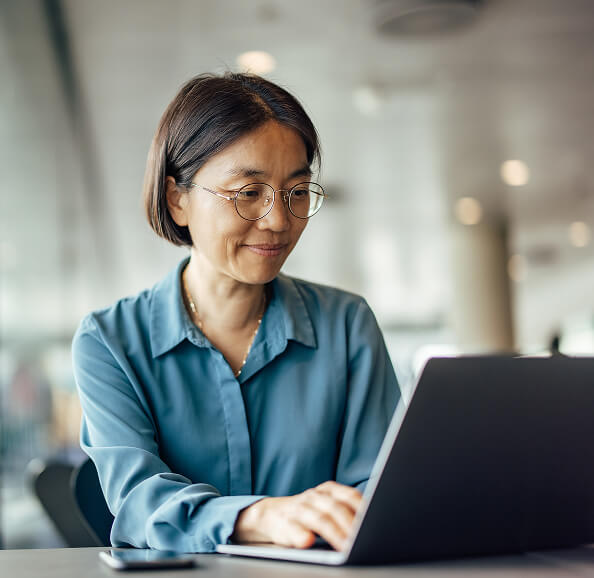 A woman smiling, using her laptop