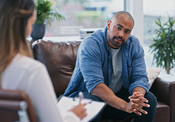 A man sitting on a sofa, talking with a practitioner